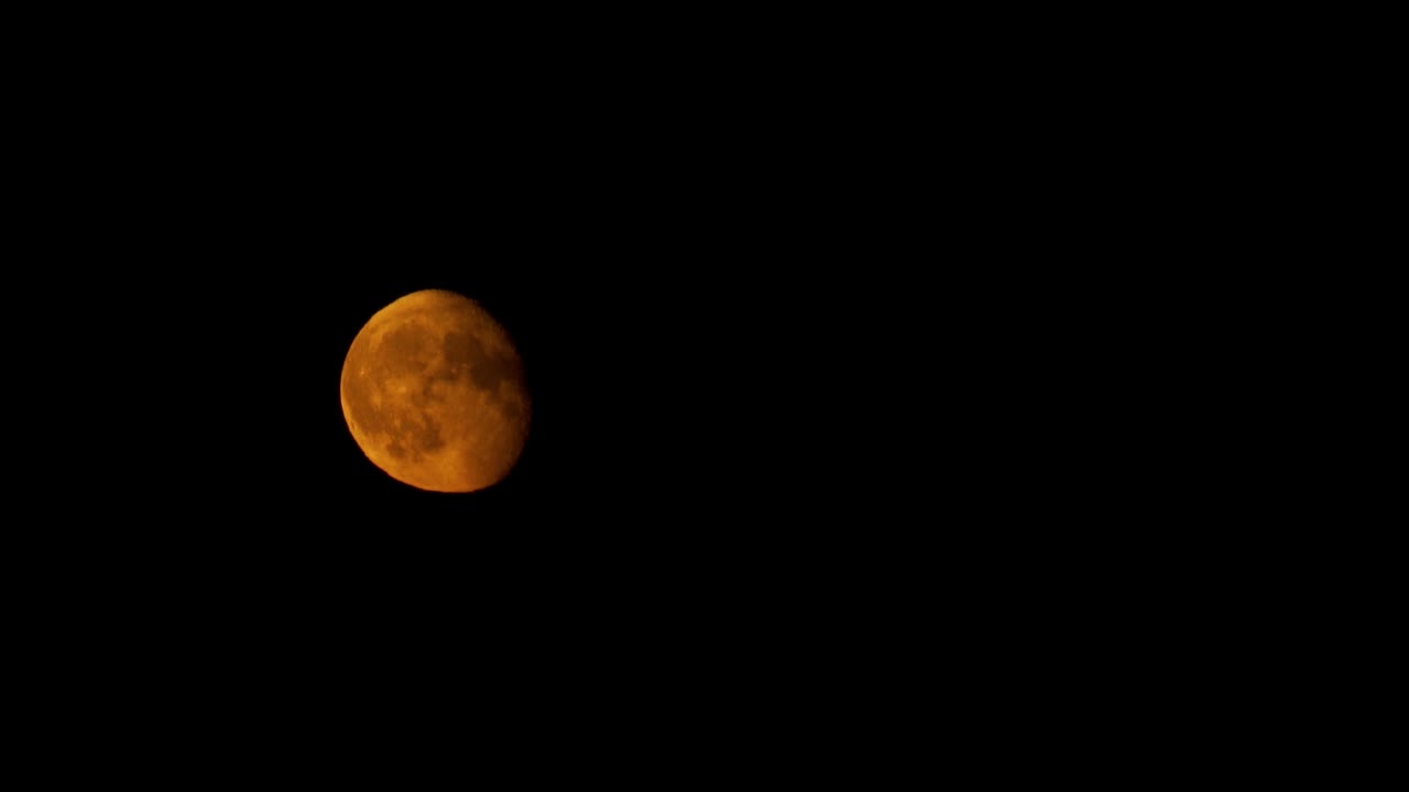 Massive red waning gibbous moon in night sky, time lapse view