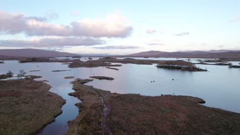 un dron se eleva lentamente y se inclina hacia un paisaje de islas entre lagos de agua dulce y turberas al atardecer