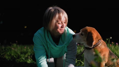 pet owner kneels on grassy field warmly kissing her beagle dog on nose during joyful bonding moment in serene park evening, surrounded by wildflowers under glowing sunset light and soft breeze