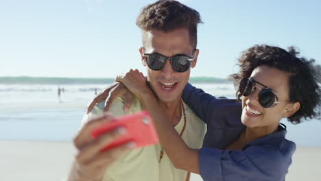 hermosa pareja de raza mixta tomando selfies en la playa