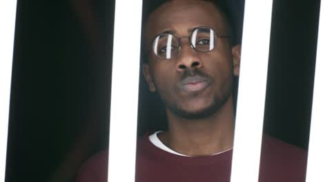 defiant black man posing behind fluorescent tubes