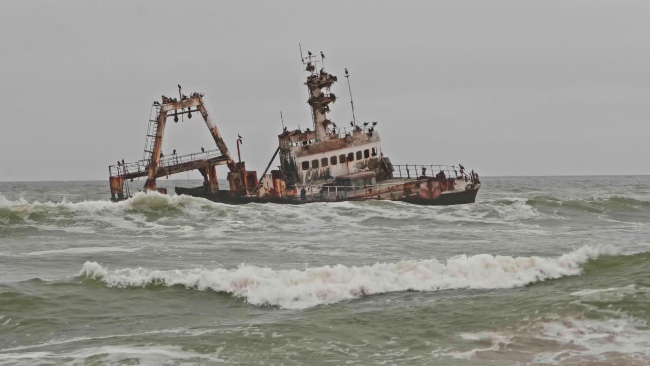 Tilt up revealing eerie shipwreck along Namibia Skeleton Coast on overcast day