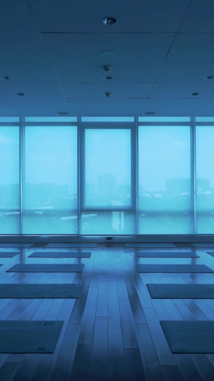 Vertical video: Recording camera framing empty yoga studio with mats, glass, sensor and city view