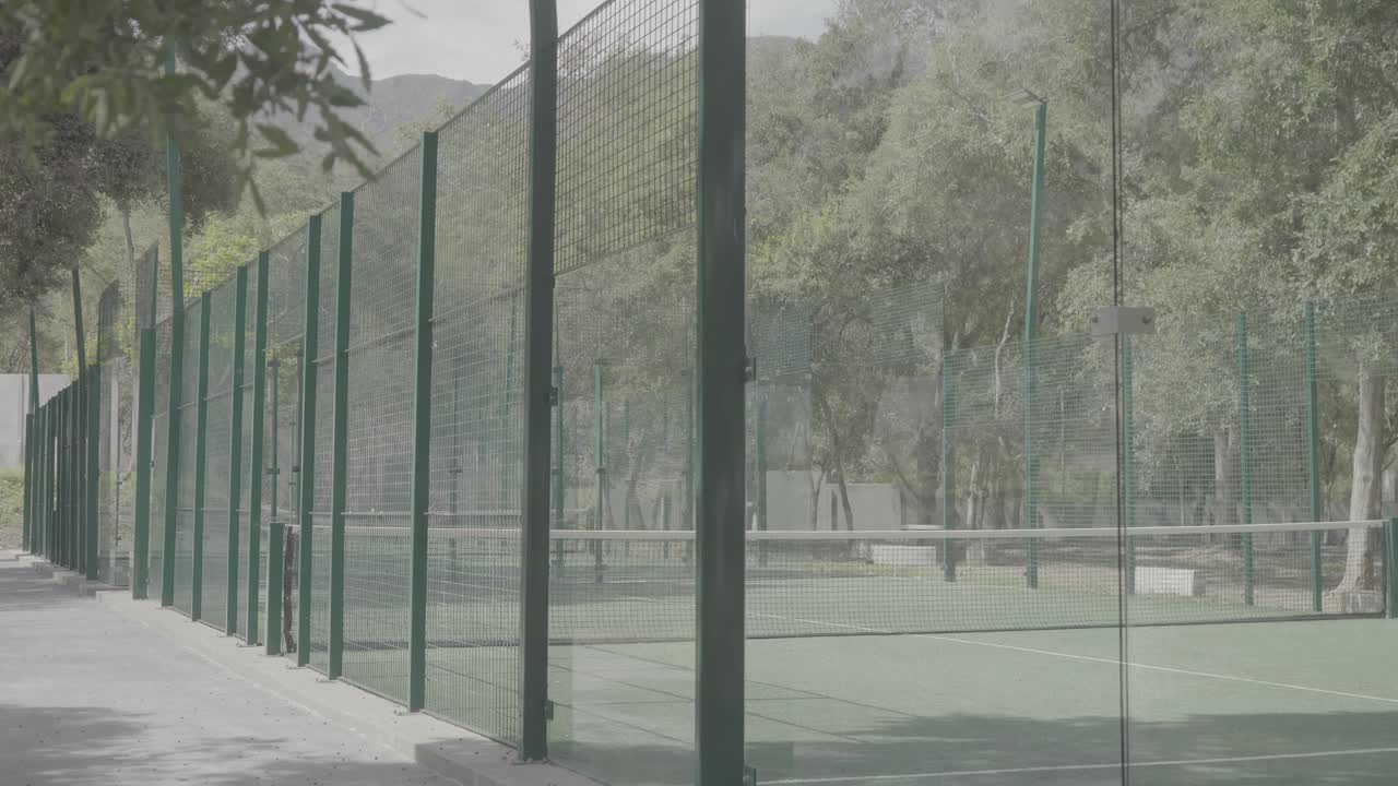 Slow establishing shot of a newly constructed paddle court surrounded by a fence
