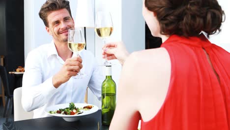 Couple-toasting-wine-glasses-while-having-lunch-in-a-restaurant