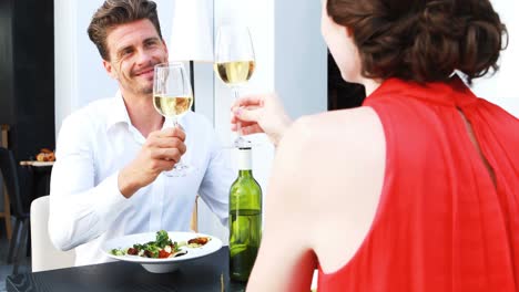 pareja brindando copas de vino mientras almuerzan en un restaurante