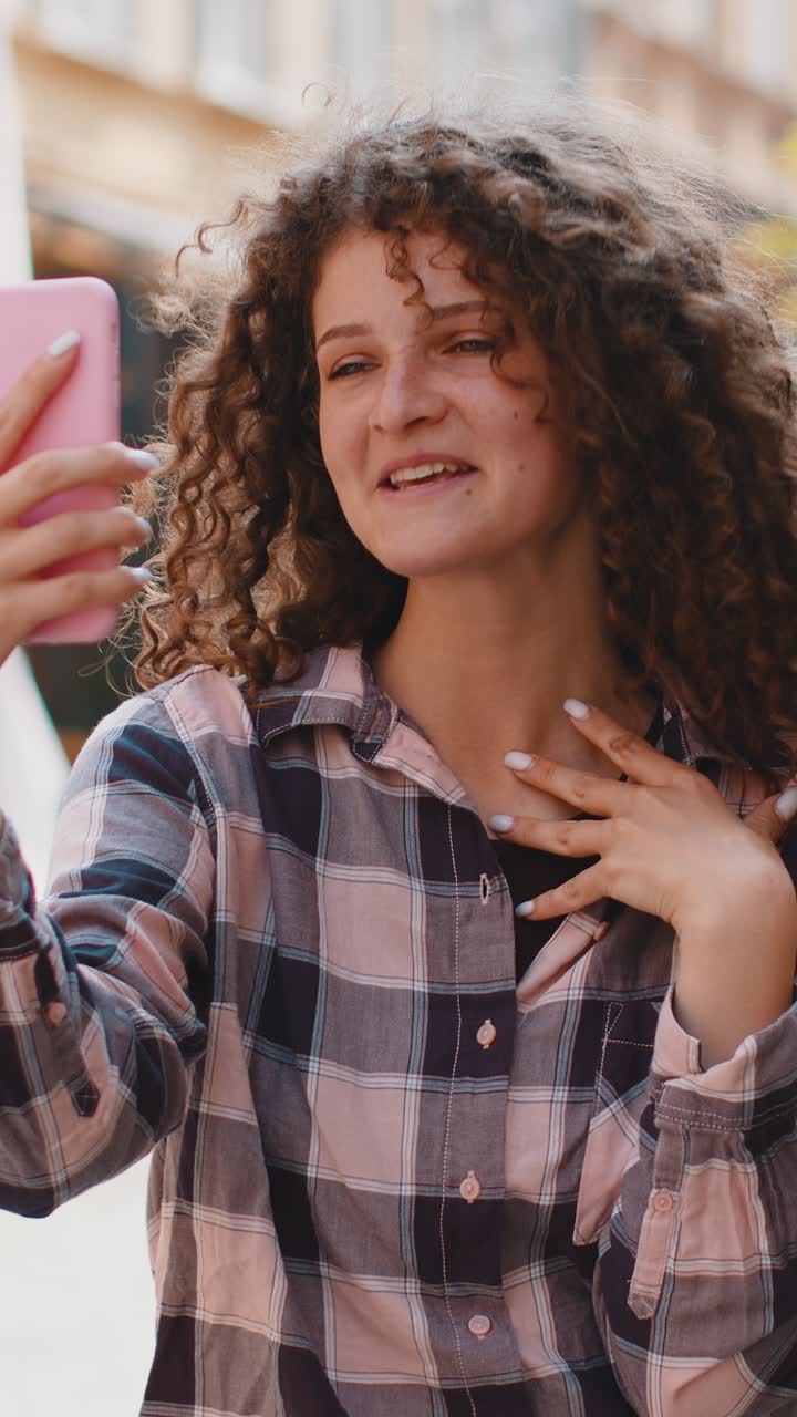 Giovane blogger che si fa un selfie con lo smartphone e fa una videoconferenza online con gli abbonati in una strada della città