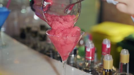 man pouring strawberry smoothies in glass from blender cup, close up view in slow motion