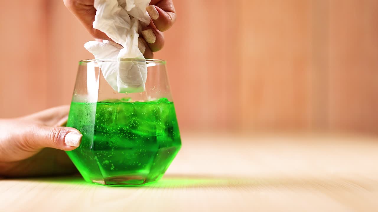 손 기 유리, 티슈 및 녹색 액체