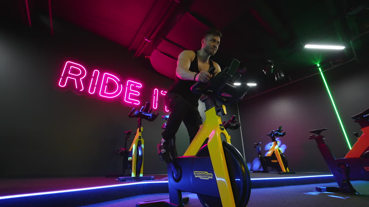 Sport man exercising in fitness club. Hard working young athlete trains on spinning exercise bike