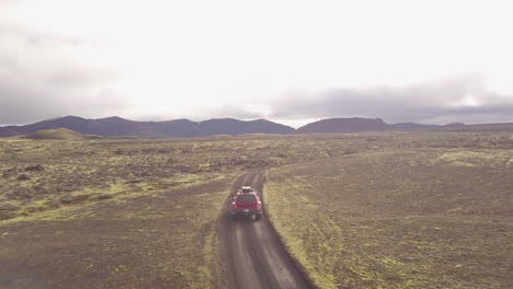 red jeep driving through icelandic lava fields