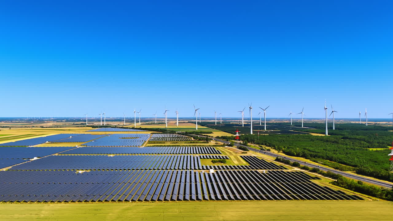 Alternative sources of energy in the rural area. Wind farms and solar panels in the countryside from aerial perspective
