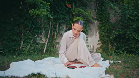 serene lady turning pages book at picnic on meadow. relaxed woman reading novel