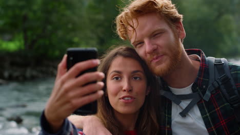 Tourists-video-chatting-on-phone-during-hike.-couple-gesturing-hands-at-camera