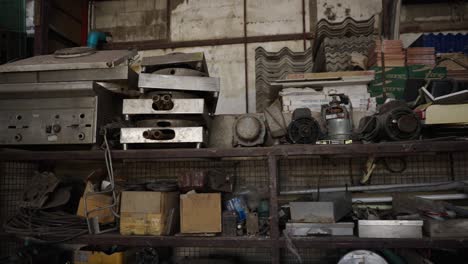 cluttered industrial storage shelf with old machinery and building materials