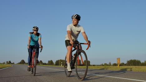 hard training.triathlete two cyclist training on road bicycle. two cyclist riding on road bike in city park and getting ready for triathlon.fit athlete intensive training two man and woman cycling before triathlon competition.