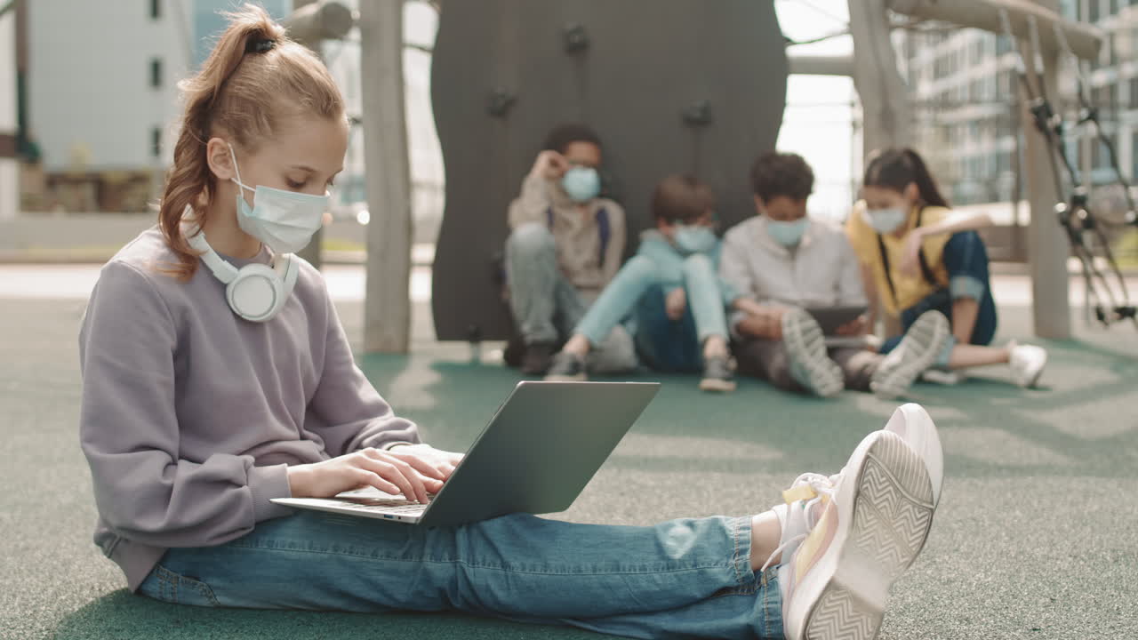 Schoolgirl in Face Mask Using Laptop Outdoors