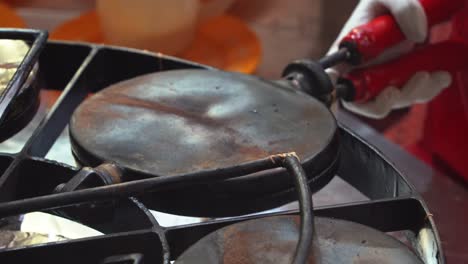 close up shot of traditional method of making ice cream waffle cone, heated cast iron spinning and rotating, butter crepe making in progress, preparation of brittle, cone-shaped pastry