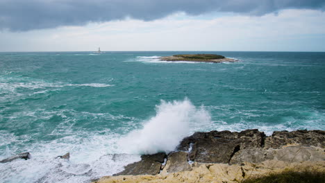 Sea-waves-breaking-on-lighthouse-Porer,-Fenoliga-island-and-rocky-coast-on-stormy-weather