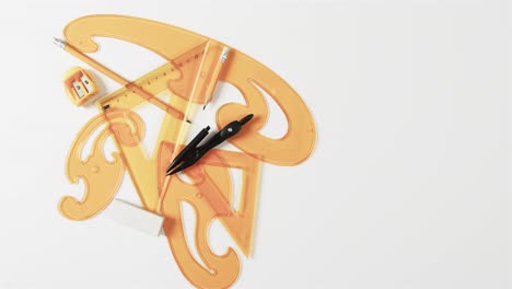 compass, pencil, sharpener, eraser and rulers with copy space on white background, slow motion