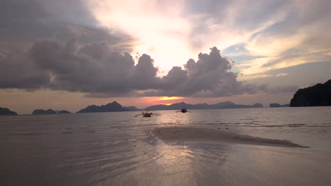 boats floating in the ocean during sunset