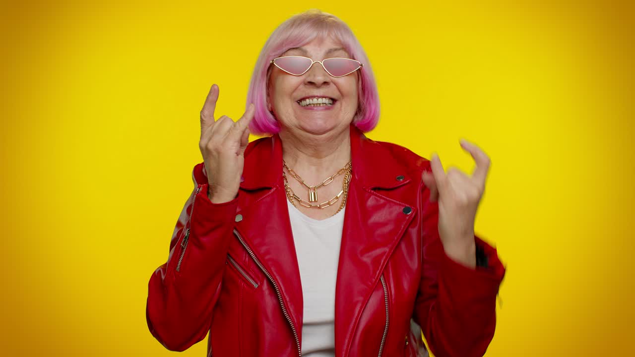 Anziana donna euforica, felicissima e scatenata che mostra il gesto rock 'n' roll con le mani, un segno di entusiasmo, ballando