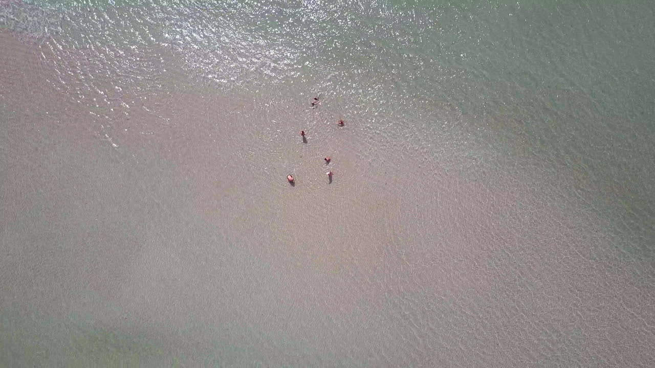 조용한 반도의 해변에서 휴식을 취하는 사람들의 그룹의 회전 드론 뷰