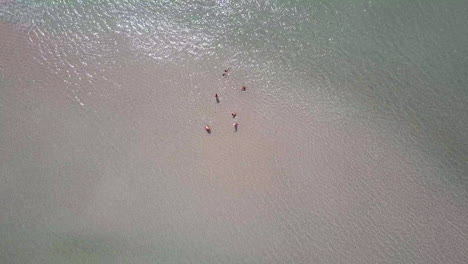 vista giratoria de un dron de un grupo de personas relajándose en la playa de una península tranquila
