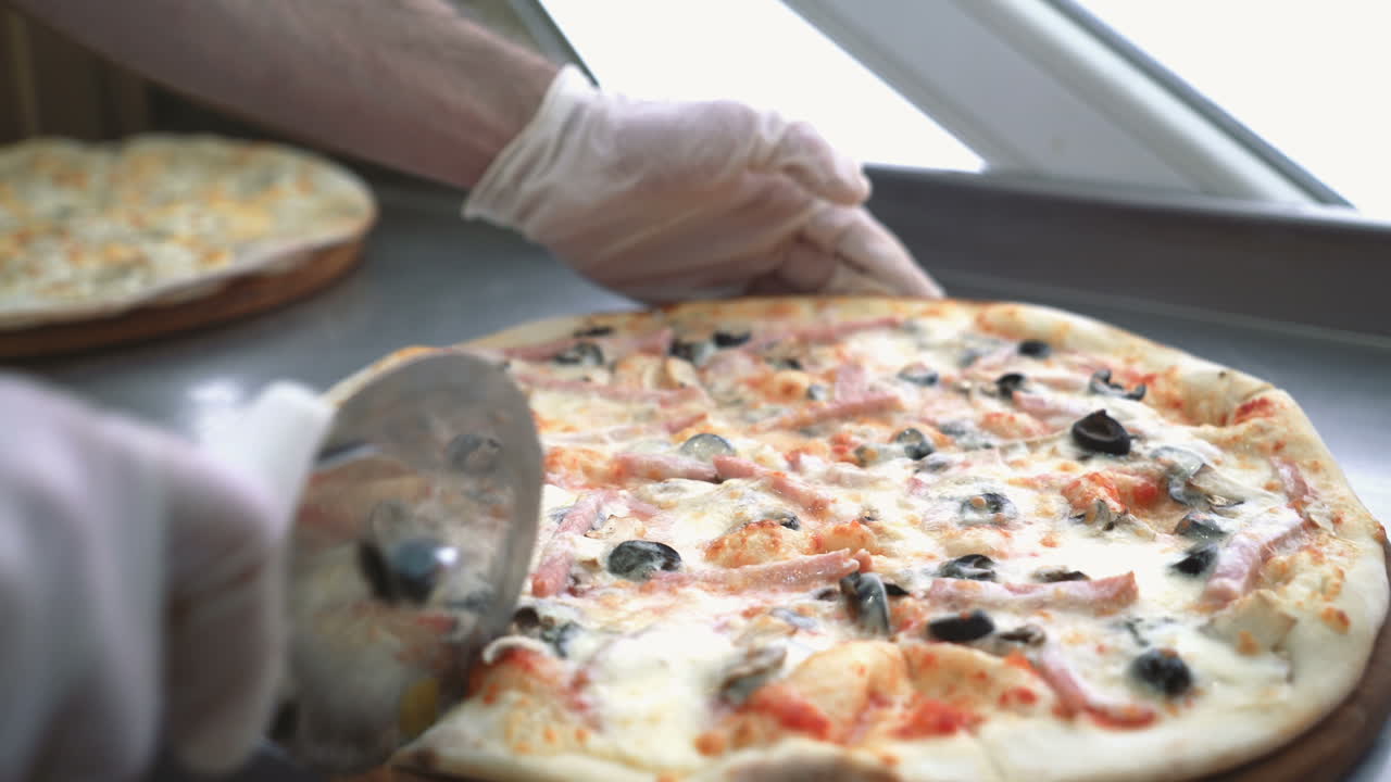 Chef cuts freshly prepared pizza slices