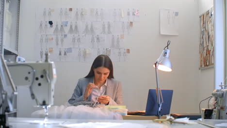 a young girl designer sewing a dress in the studio dress. making clothes sewing beads and jewelry. seamstress decorates a dress in the studio.