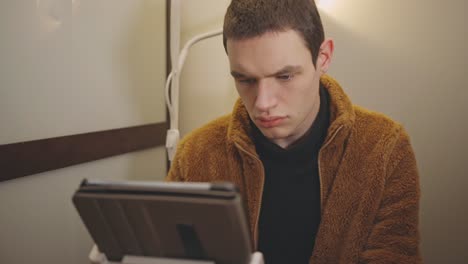 Young-Male-Professional-Working-At-Home-With-His-Tablet-Fixed-On-Desk-Tablet-Holder---Medium-Closeup-Shot