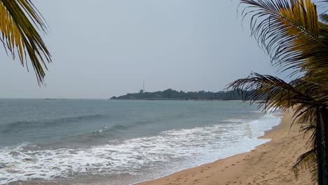glimpse of white sand and ocean at tangalle beach through coconut palm trees in southern province sri lanka
