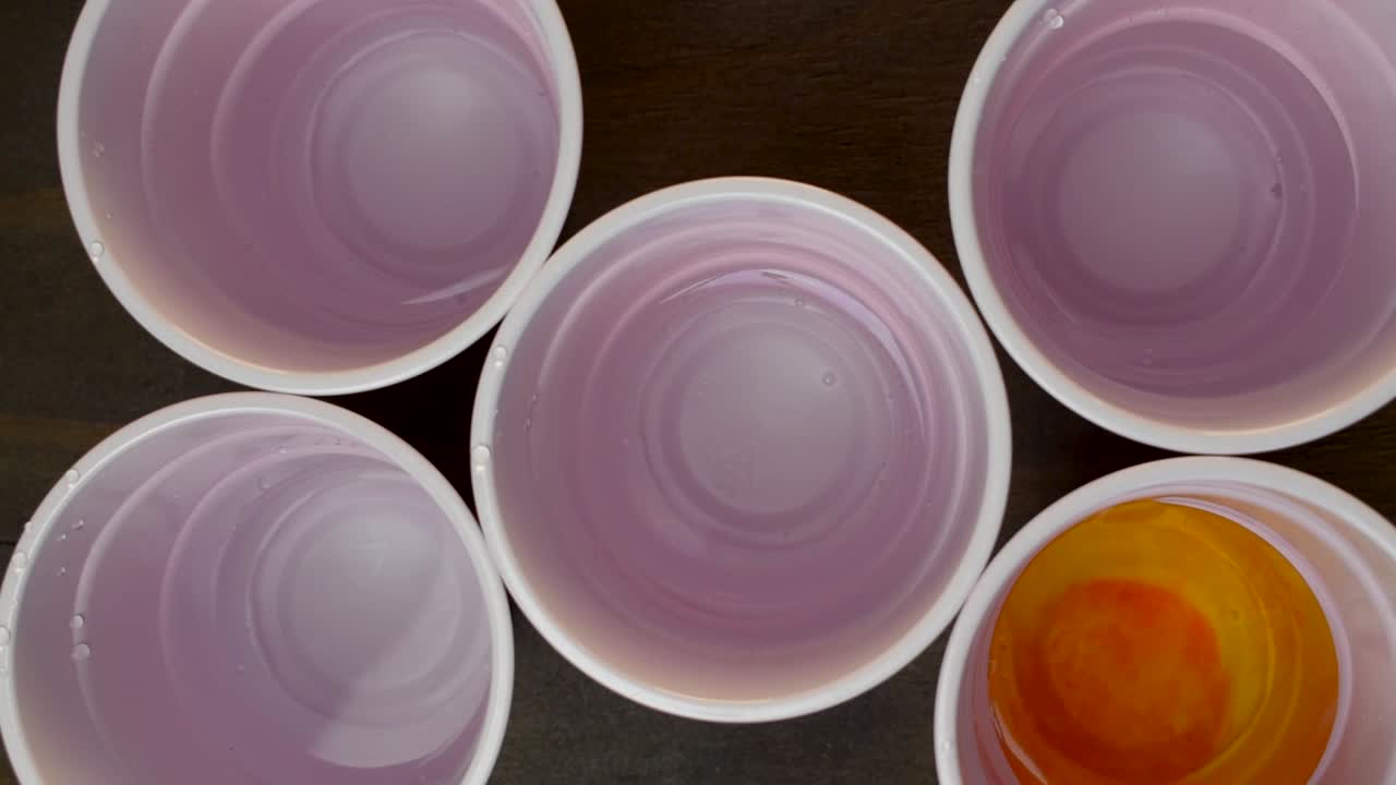 다양한 색상의 식용 색소가 첨가되고 저어지는 물 5컵의 상위 뷰