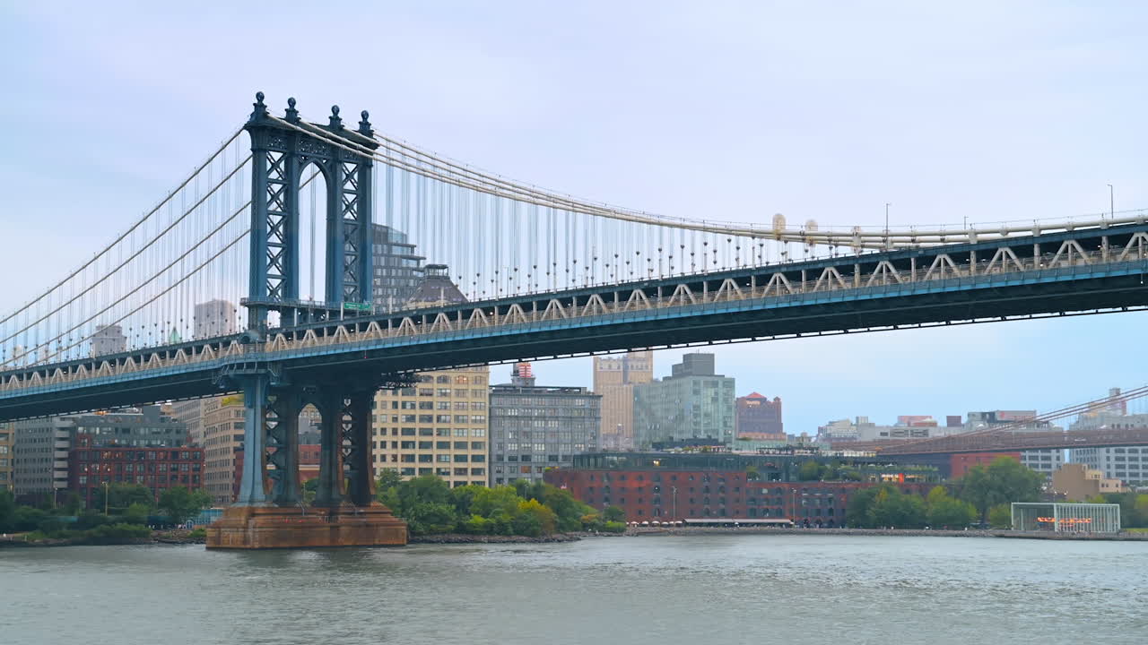Side view of Manhattan Bridge over the East River. The Manhattan Bridge stretches across the East River with city buildings in the distance