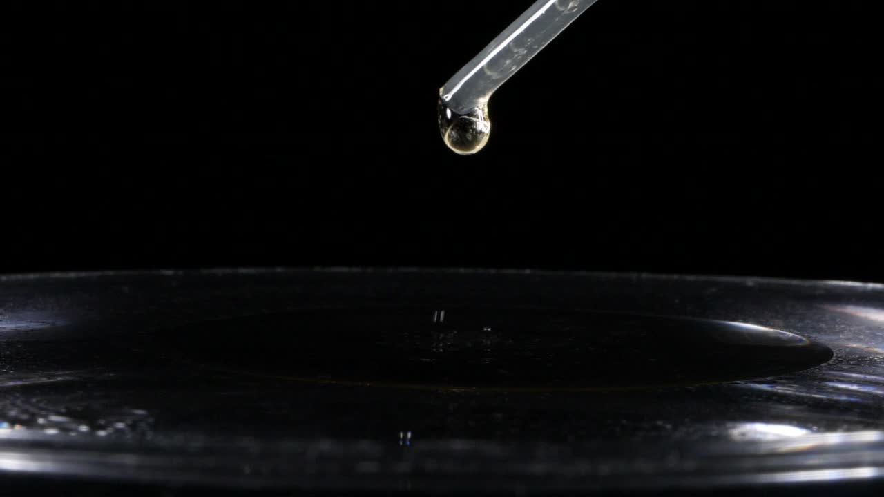 무거운 액체 방울이 피펫, 향수, 의료, 검정색 배경에서 떨어집니다.