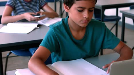 schoolboy using laptop while studying in classroom