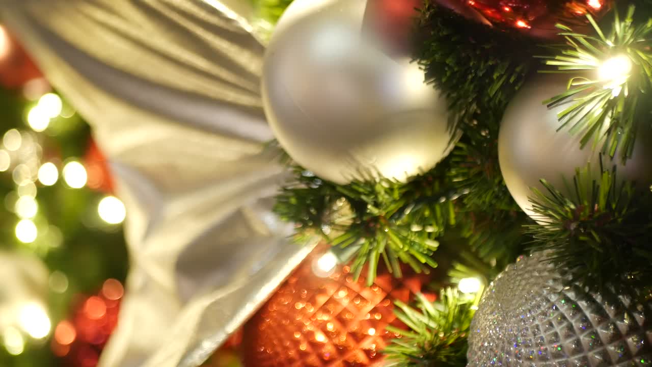 primer plano de un árbol de navidad al aire libre decorado festivamente con bolas rojas brillantes en un fondo de hadas brillantes borrosas. luces de guirnaldas desenfocadas, efecto bokeh. feliz navidad y feliz concepto de vacaciones.