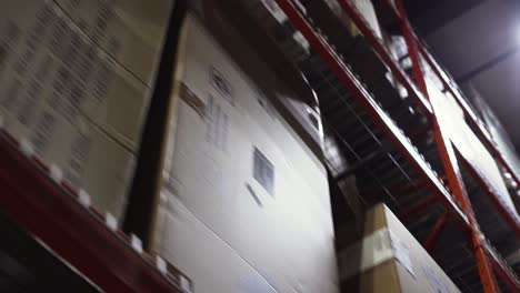 driving a case picking machine down a distribution centre warehouse isle passing industrial racks boxed and wrapped with commercial furniture retail products