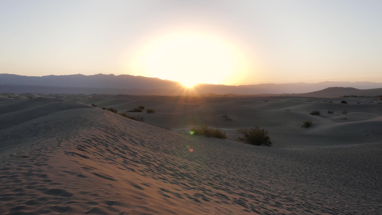 el sol se levanta sobre las dunas de arena en el parque nacional del valle de la muerte en cámara lenta - la cámara se inclina hacia arriba