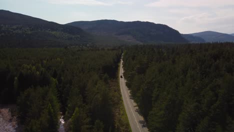 drone pushin shot of scotland hills with car driving into distance on road