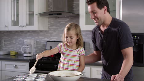 caucasian girl spooning out cake mix mix for baking with her dad, shot on r3d