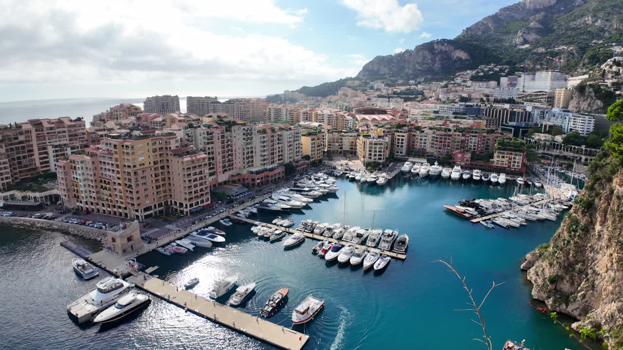 Vista dall'alto di Port de Fontvieille a Monaco, con edifici colorati, yacht di lusso e il paesaggio montuoso circostante