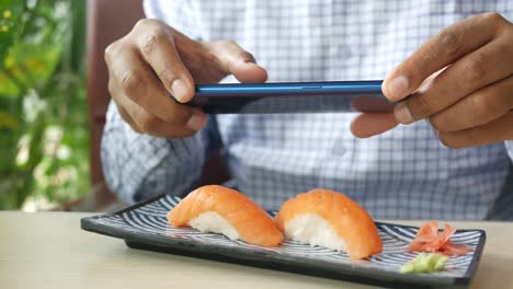 person taking a picture of salmon sushi with a smartphone