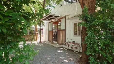 Dolly-Shot-of-a-Coffee-Shop-Entrance-with-Bicycle-Resting-Against-a-White-Wall-Under-a-Window