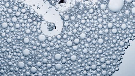 multitude of air bubbles in a soap solution, bubbles burst on contact with air