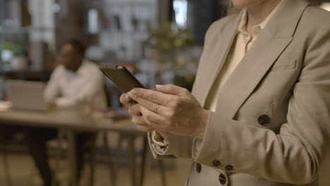 Close-Up-Of-Female-Hands-Texting-On-Mobile-Phone-In-The-Office-1