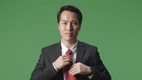 asian business man in jacket and white classic shirt wearing red necktie. dressing for celebration event, business meeting or wedding on green screen background