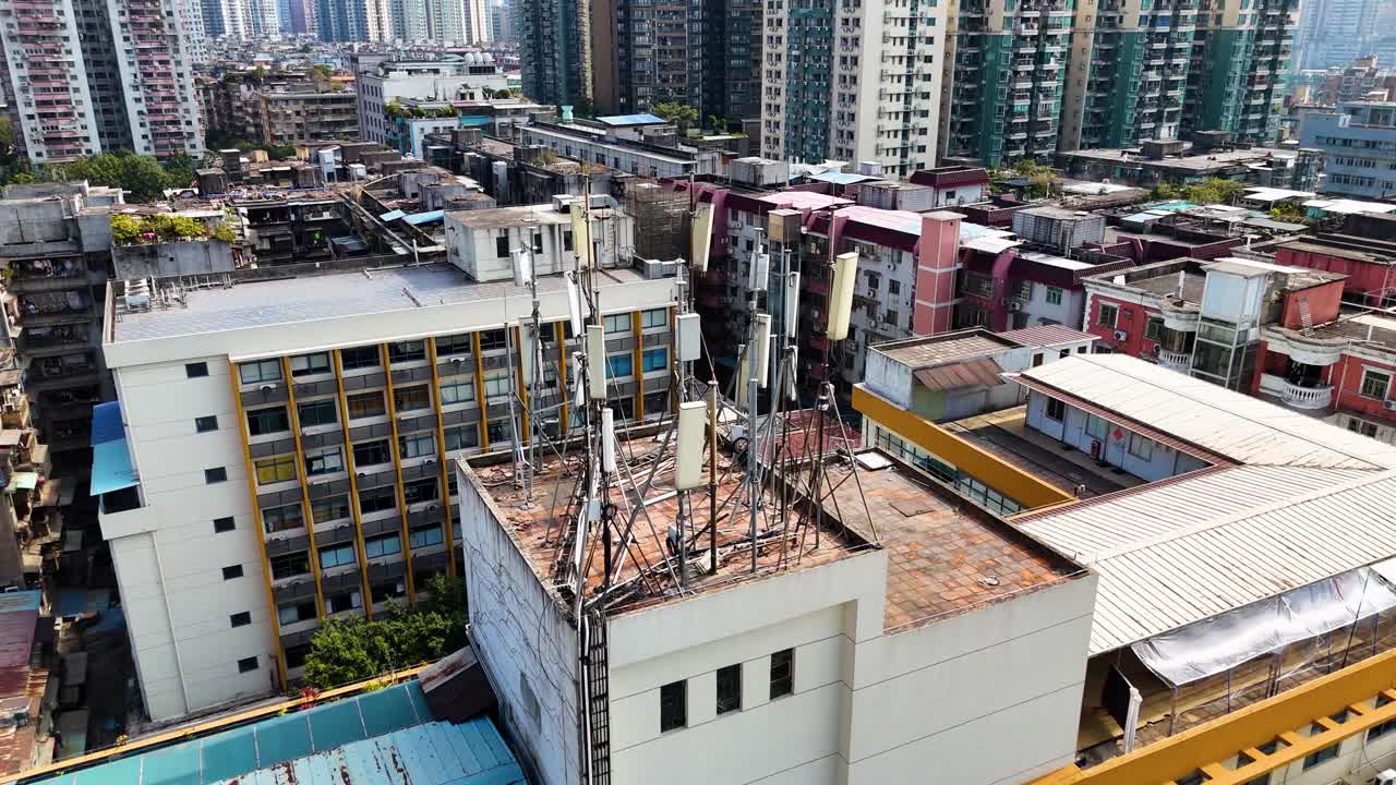 A rooftop telecommunication tower in Guangzhou, China, with multiple antennas supporting 5G network connectivity. A dense urban setting showcasing modern infrastructure and city development.