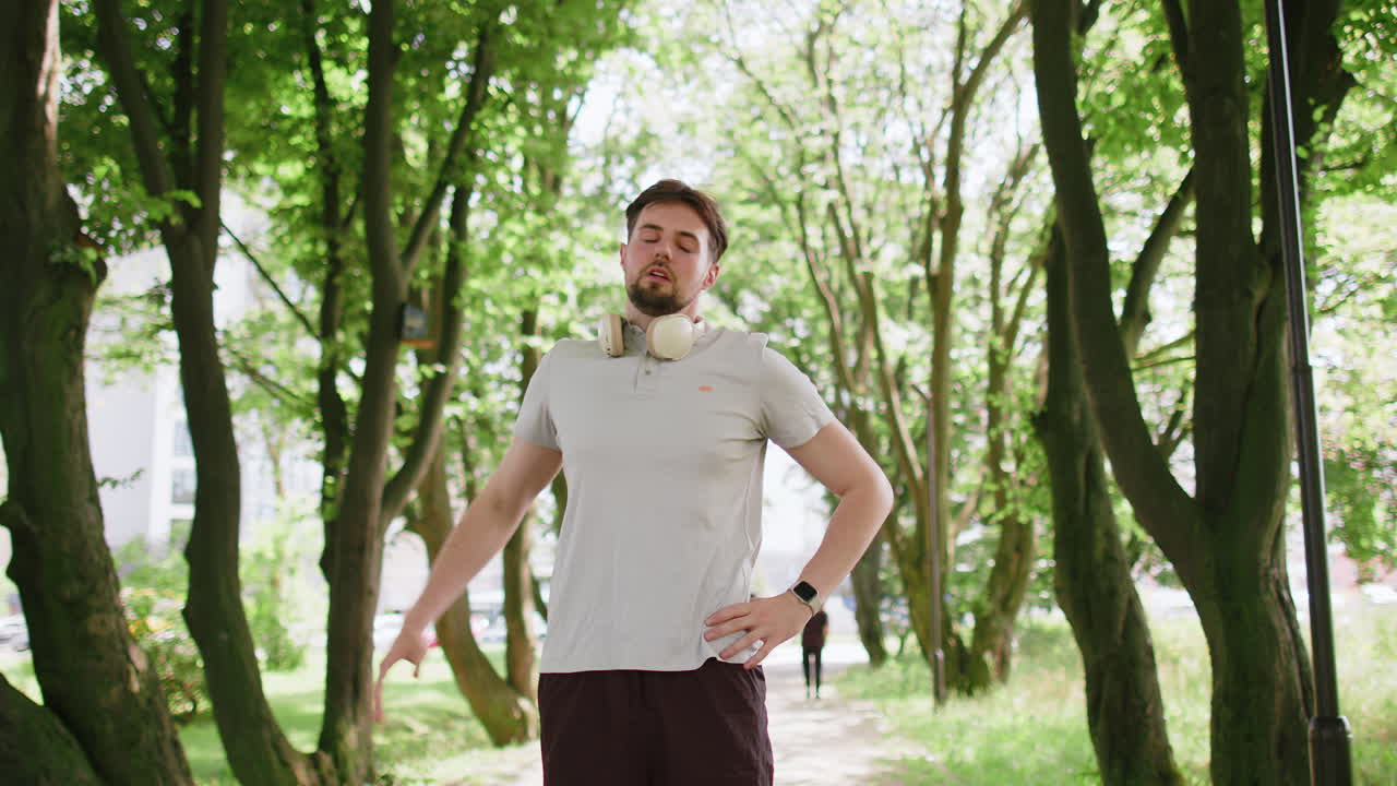 Spor giyimli atletik beyaz adam, koşu antrenmanı öncesi vücudunu esnetiyor ve ısınıyor.