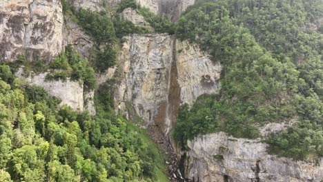 seerenbachfälle waterfall in switzerland, drone pull back shot, cliffs, forest and walensee beauty